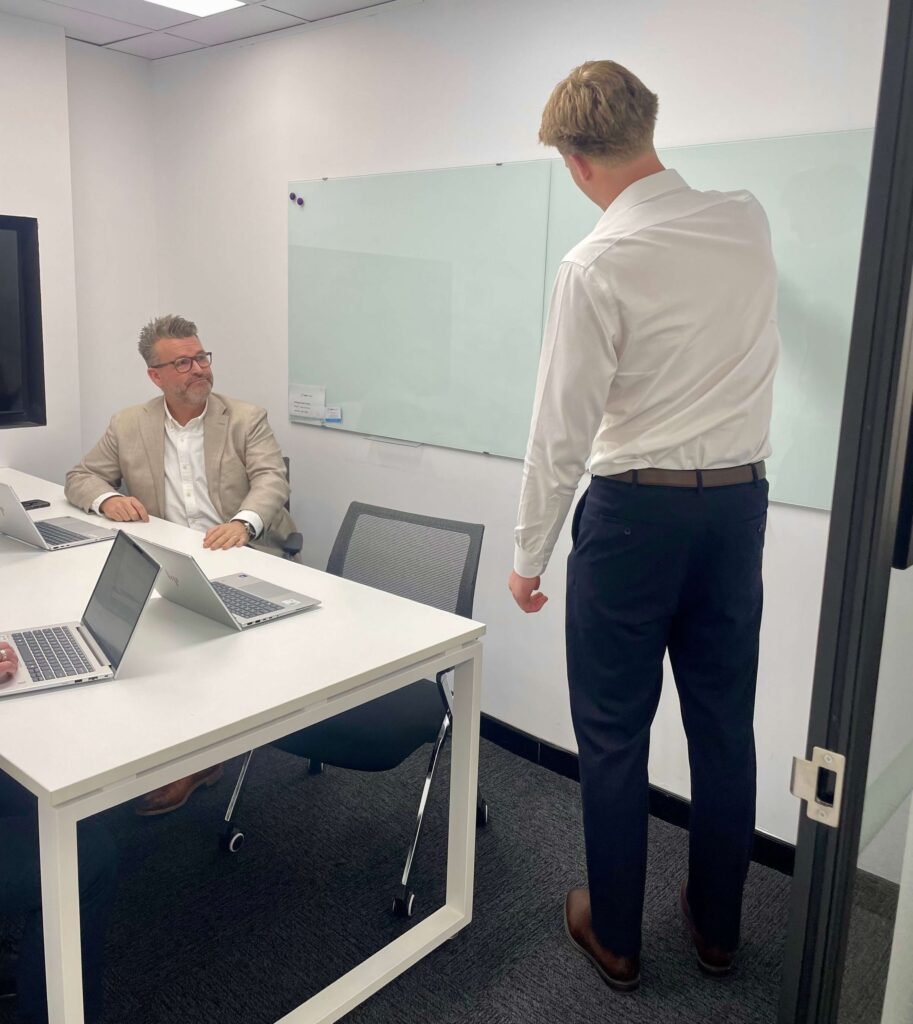 Harry presenting to colleagues during a StewartBrown team meeting in the Inspire Cowork Miranda boardroom.