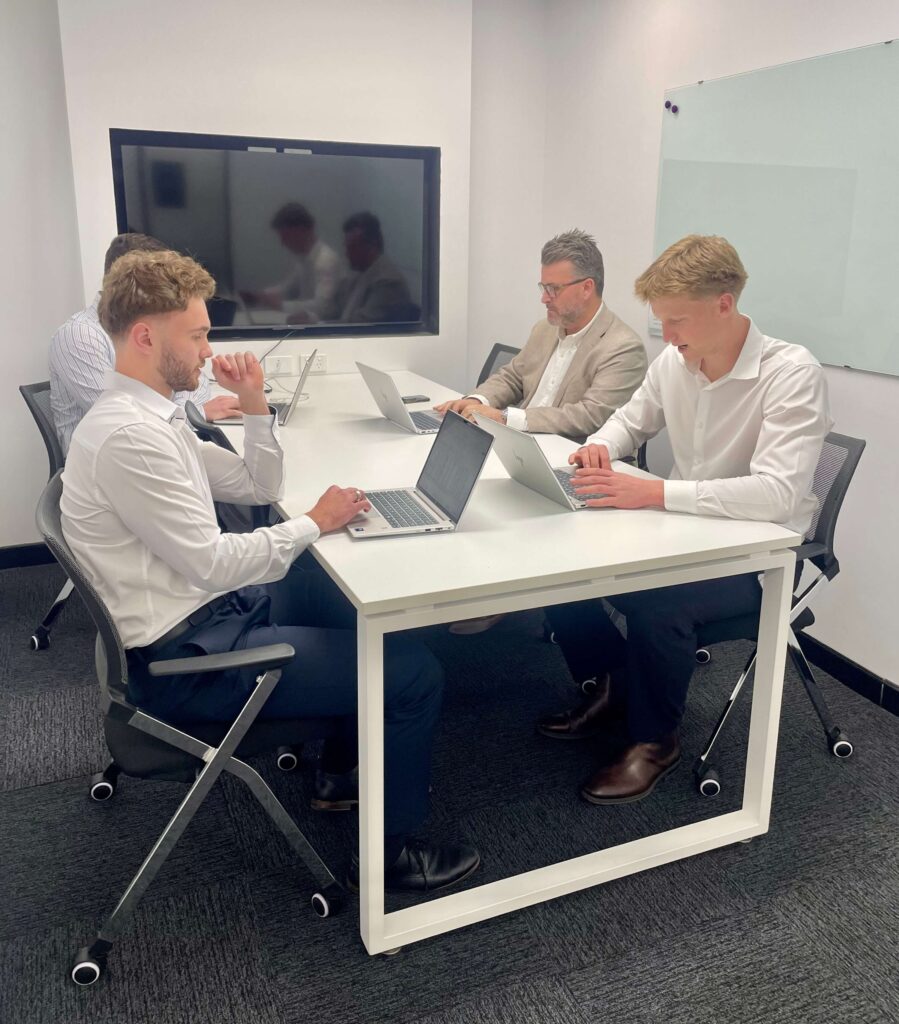 StewartBrown team members discussing client work around the boardroom table at Inspire Cowork Miranda.