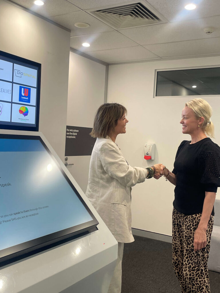 Sandra Moscardo speaking with a client beside the reception area at Inspire Cowork Miranda.
