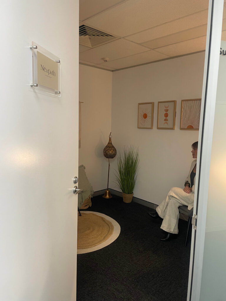 Open doorway leading into a private consulting room with chairs and wall artwork visible inside.